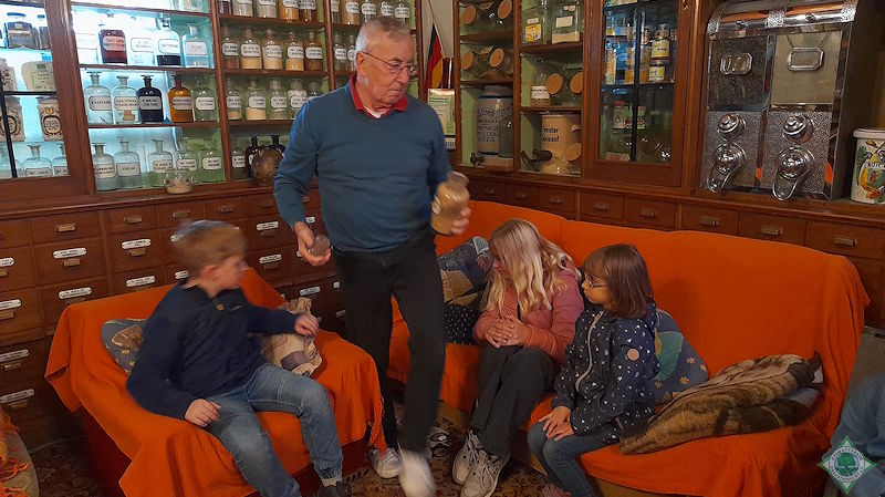 Heinz Töns (Mitte) erläutert den Kindern die Arzneimittel im Drogeriemuseum. Foto: Silvia Lütkehellweg