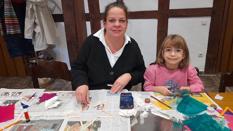 Auf dem Bild ist die Gruppenleiterin gemeinsam mit einem Mädchen beim Basteln von Transparentsternen aus Holzstäben zu sehen. Foto: Silvia Lütkehellweg